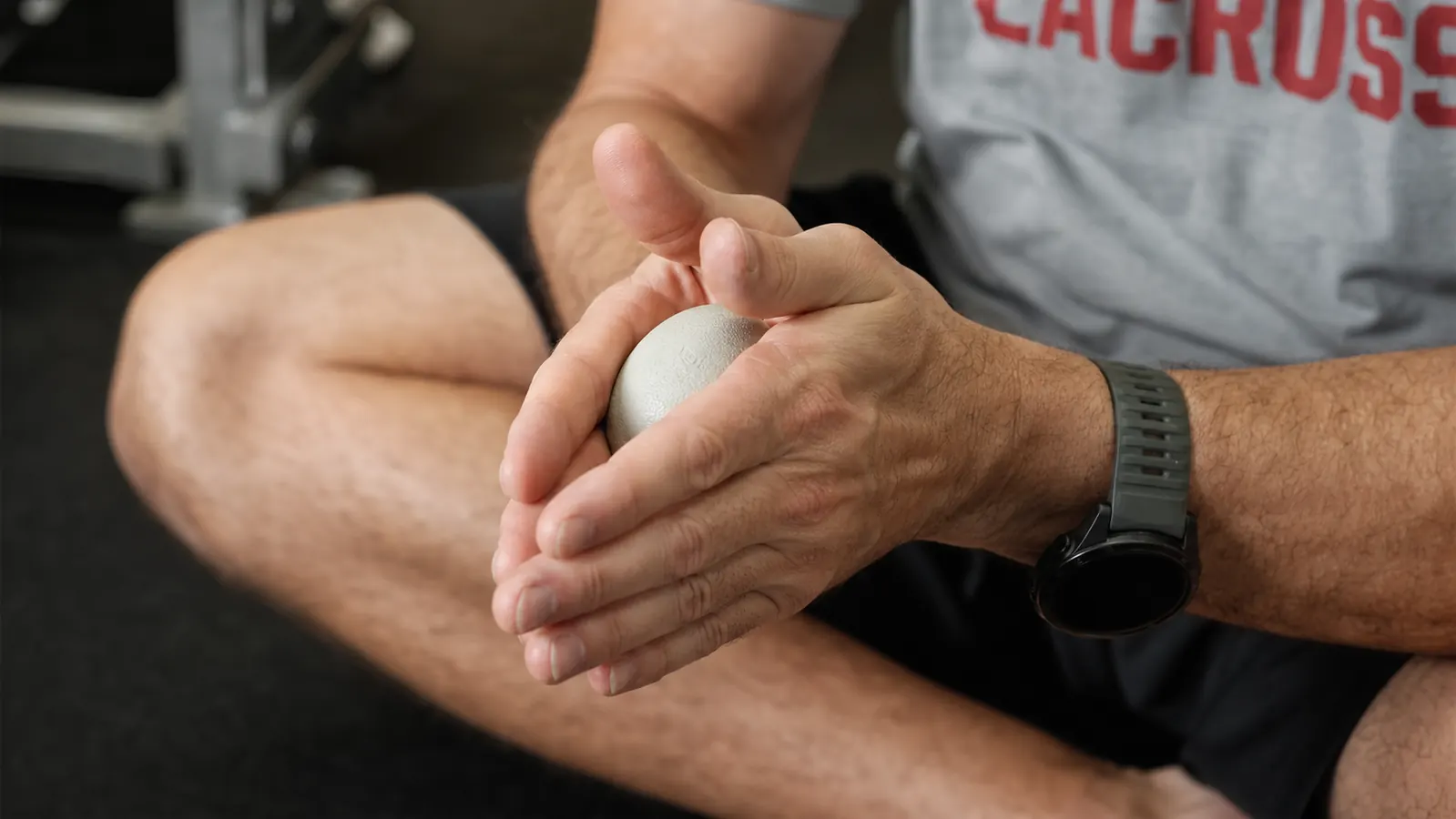 Man sitting on a gym bench post-workout, one Kieba ball in hand, looking relaxed and thoughtful