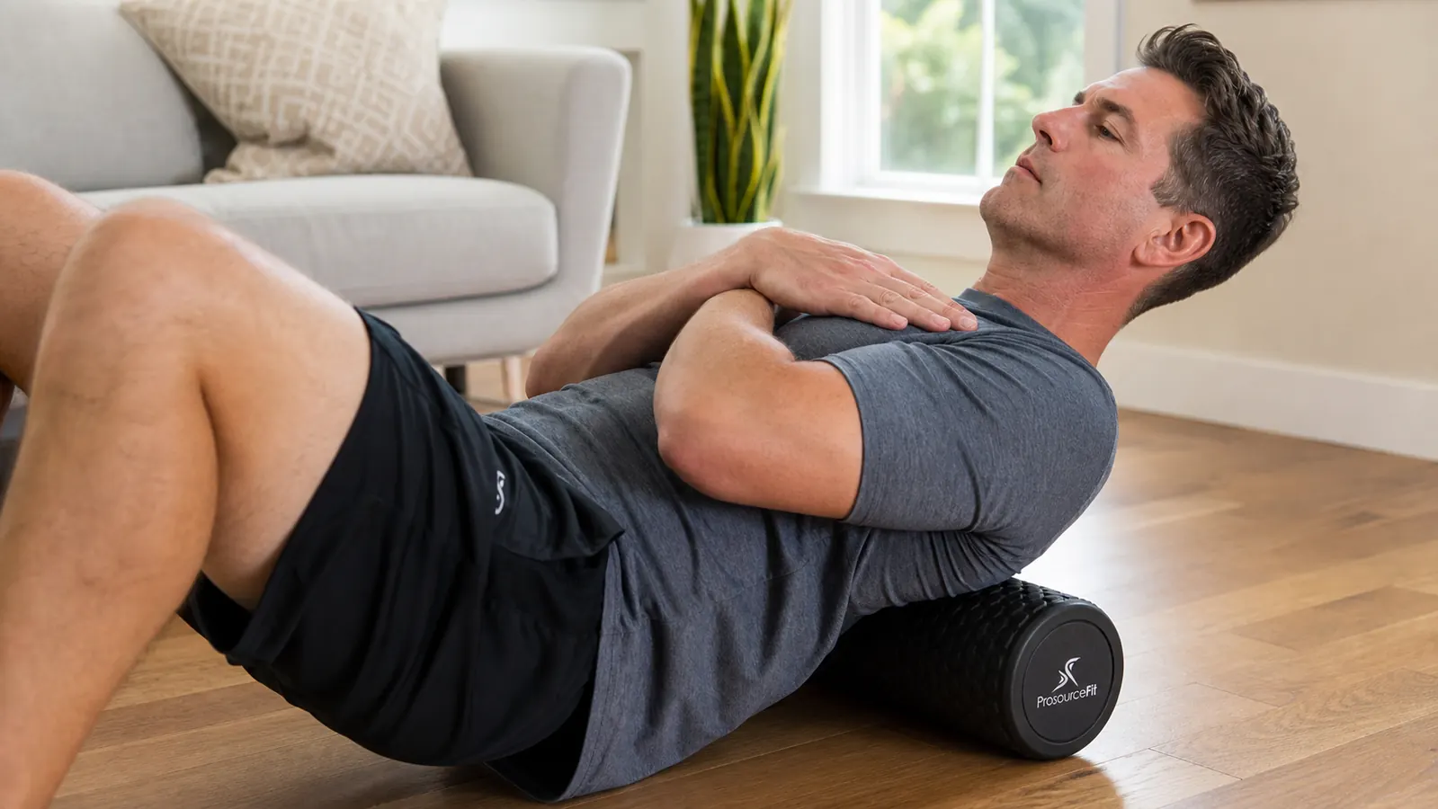 Man pressing his forearm into a foam roller to test density, concrete garage floor background